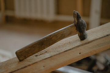 a hammer lies on a wooden beam, a construction tool