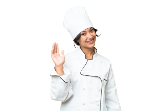 Young chef Argentinian woman over isolated background saluting with hand with happy expression