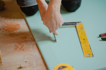 a worker cuts a flat sheet on a wall with a construction knife, construction process, interior wall...