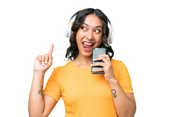 Young caucasian Argentinian woman over isolated background listening music with a mobile and singing