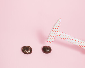 Hammer wrapped in dotted paper breaks the chocolate on bright pink background. Nail the New Year resolution diet concept. Creative way to quit eating sweets idea.