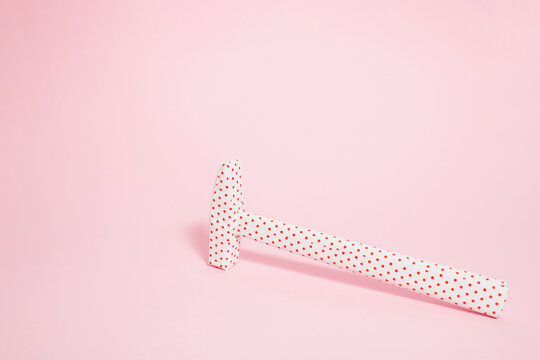Hammer wrapped in dotted paper on bright pink background. Nail the  New Year wishes concept. Creative Christmas gift wrapping idea.