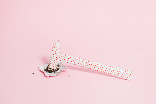 Hammer wrapped in dotted paper breaks the chocolate on bright pink background. Nail the New Year resolution diet concept. Creative way to quit eating sweets idea.