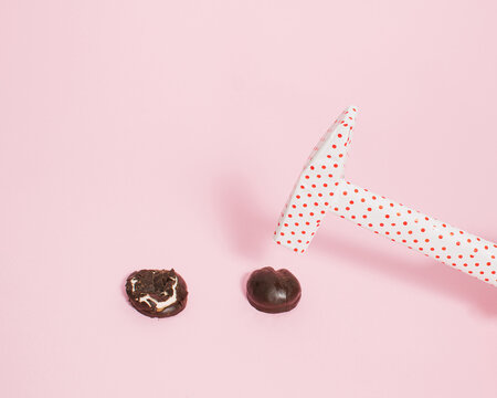 Hammer wrapped in dotted paper breaks the chocolate on bright pink background. Nail the New Year resolution diet concept. Creative way to quit eating sweets idea.