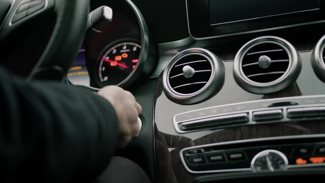 man inserts the key into the ignition of an expensive luxury car and starts the car