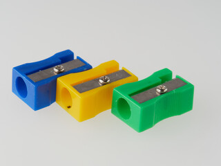 some colored pencils of different colors and a pencil sharpener and pencil shavings on a white background