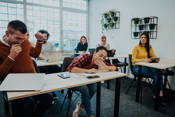 A group of diverse people listen to a lecture in business training while sitting in a modern classroom