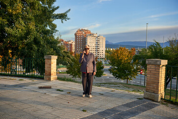 older woman with sunglasses talking on the phone with city buildings in the background