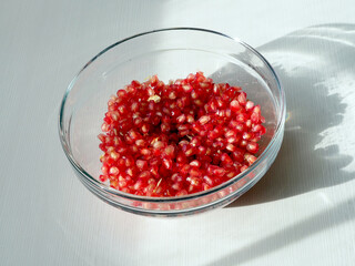 Pomegranate seeds in a glass bowl on white table