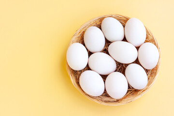 White eggs in basket on yellow background, Duck eggs.
