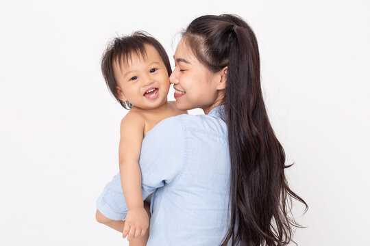 Asian mom hold baby smile and kissing on baby cheek happiness moment together isolated on white background. Healthy Mother and baby boy smile and laughing spending time together positive and cheerful.