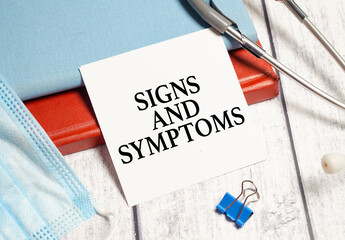 signs and symptoms words on with sticker near red notebook with stethoscope