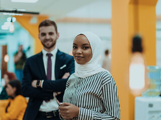 Portrait of a formal businessman and young African American businesswoman posing with their team in a modern startup office. Marketing concept. Multi-ethnic society.