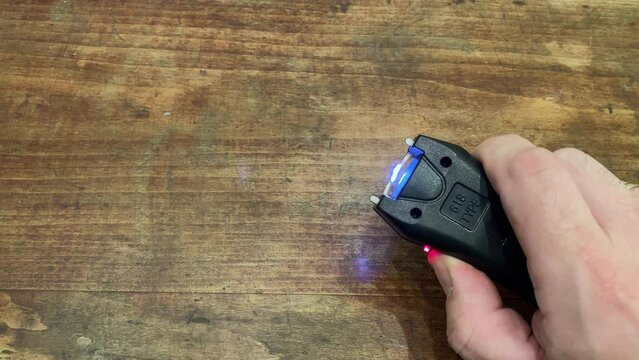 Compact stun gun in hand. Means of protection against bullies. Electrocute.