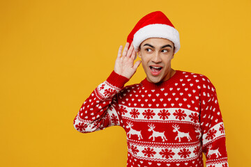 Merry nosy curious young man wear knitted xmas sweater Santa hat posing try to hear you overhear...