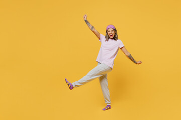 Fototapeta na wymiar Full body side view happy young woman she wears purple pyjamas jam sleep eye mask rest relax at home go with outstretched hands isolated on plain yellow background studio portrait. Night nap concept.
