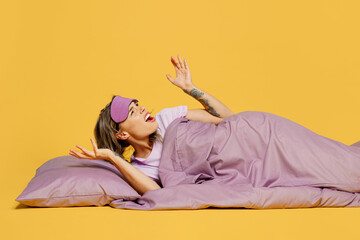 Full body young woman wear purple pyjamas jam sleep eye mask rest relax at home lying on pillow...