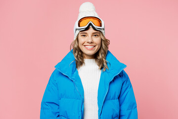 Snowboarder smiling happy woman 20s wear blue suit goggles mask hat ski padded jacket spend extreme weekend look camera isolated on plain pastel pink background. Winter sport hobby trip relax concept.