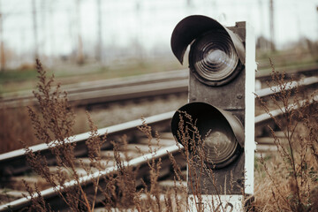 A weathered railway signal stands beside overgrown tracks, hinting at a forgotten or less-used...