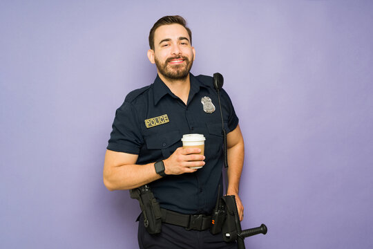 Happy male police officer enjoying coffee while on duty