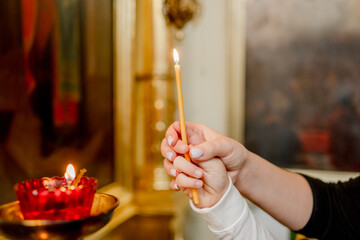 The hand of a woman and a child put a candle in the Church