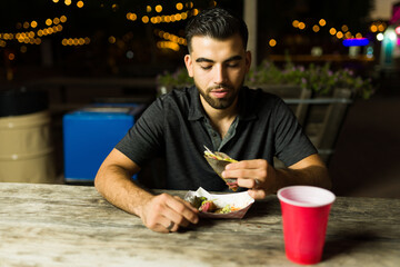 Latin young man eating mexican tacos at the food cart