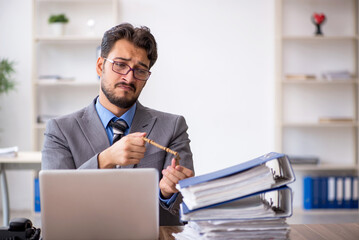 Young male employee unhappy with excessive work in the office