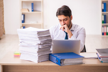 Fototapeta premium Young businessman employee unhappy with excessive work in the office