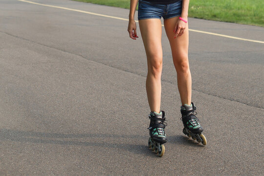 cropped image of legs of woman roller skating on asphalt road
