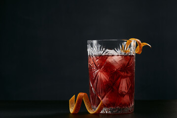 Negroni cocktail in a rock glass with orange peel on a dark background.
