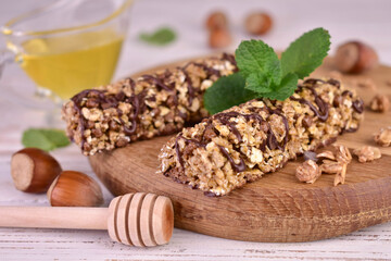 Two muesli bars with chocolate and honey on a wooden board.
