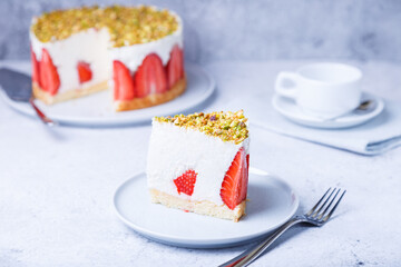 Freesier cake with fresh strawberries and pistachios. French classic dessert. Portion of cake on a white plate. Selective focus, close-up.