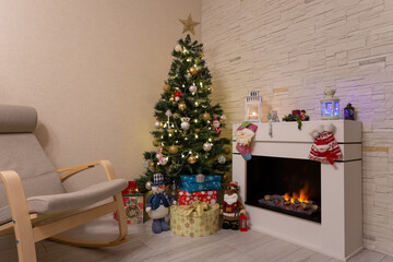 Decorated Christmas tree, gifts in boxes, a Santa Claus statuette, a burning fireplace. New Year, Christmas. Copy space. Selective focus, close-up.
