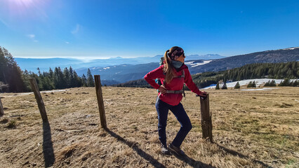 Woman on hiking trail standing next to fence on alpine meadow near Ladinger Spitz, Saualpe,...