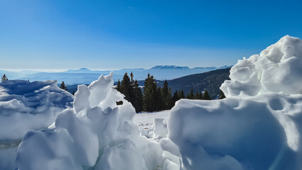 Fototapeta na wymiar Natural snow formations with scenic view of alpine meadows, hills and forest seen from hiking trail on Saualpe, Lavanttal Alps, Carinthia, Austria, Europe. Untouched snow fields. Ski touring tourism