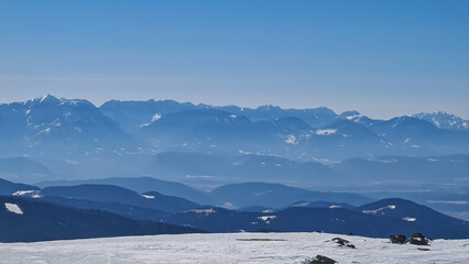 Panoramic view on snowcapped mountain ranges of Karawanks and Kamnik Savinja Alps seen from mountain peak Grosser Sauofen in winter on Saualpe, Lavanttal Alps, Carinthia, Austria, Europe. Sunny day