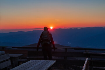 Silhouette of happy woman enjoying a beautiful sunset on mountain peak Ladinger Spitz, Saualpe, Lavanttal Alps, Carinthia, Austria, Europe. Warm atmosphere, inspiration, goal seeking concept