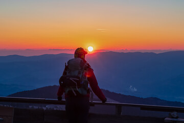 Silhouette of happy woman enjoying a beautiful sunset on mountain peak Ladinger Spitz, Saualpe, Lavanttal Alps, Carinthia, Austria, Europe. Warm atmosphere, inspiration, goal seeking concept