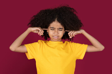 Irritated black girl close plug ears over colorful background