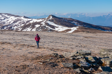 Woman hiking on frozen alpine meadow from Ladinger Spitz to Gertrusk, Saualpe, Lavanttal Alps,...