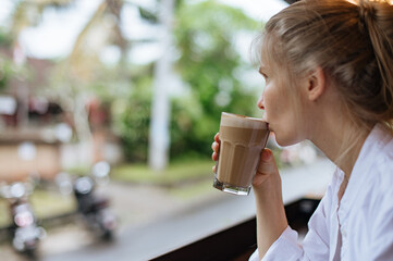Girl drinking coffee and looking outside