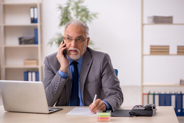 Old male employee working at workplace