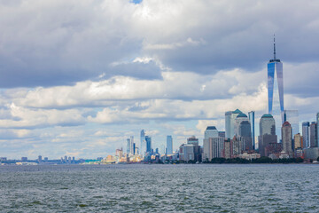 View of Manhattan skyscrapers on both sides of Hudson river under blue sky with white clouds. New York, USA.