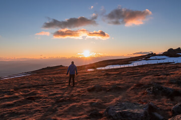 Silhouette of happy man enjoying a beautiful sunset on mountain peak Ladinger Spitz, Saualpe, Lavanttal Alps, Carinthia, Austria, Europe. Warm atmosphere, inspiration, goal seeking concept