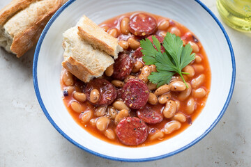 Stew with chorizo sausage and white beans served in a white plate, middle close-up, selective focus, horizontal shot
