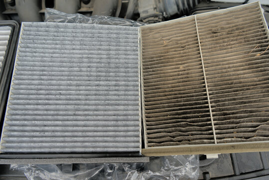 A new car air filter and an old one with garbage in the hands of a man. Comparison and preventive replacement in the car.