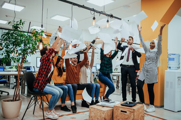 Group of business people throwing paper in air at modern startup office, team success and job done concept