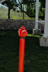 Fototapeta na wymiar Red hydrant on a green meadow. Fire safety in public places