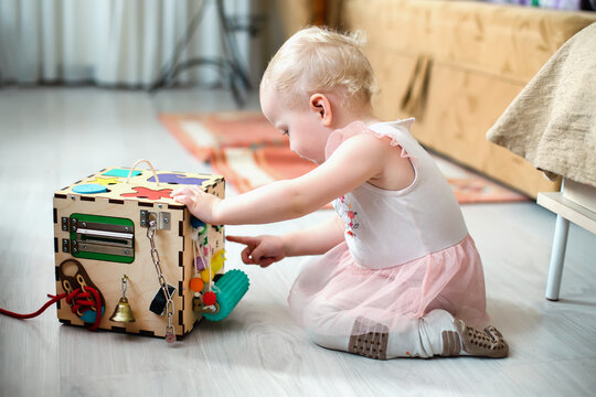 Activity Board. The baby learns the numbers on the clock on the bisiboard. Early development of children with a playful wooden cube toy Montessori.