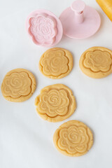 The process of making cookies with forms in the form of flowers, a rolling pin and a baking sheet - ready-made cookies with an imprint from the form. The concept of baking at home.
